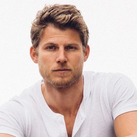 Travis Van Winkle in a white t-shirt poses for a picture.